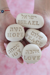 Handmade ceramic stones with Hebrew and English words: love, joy, hope, peace, and Israel – perfect for gifting